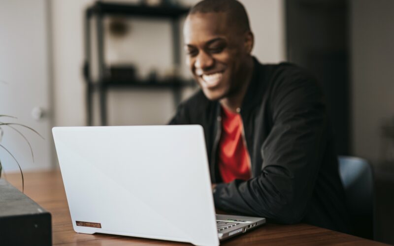 man smiling while looking at laptop screen