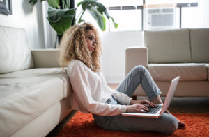 woman sitting on living room floor using a laptop