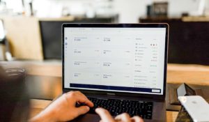 person typing on computer with financial data on the screen