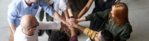 group of people putting their hands together in the middle of a huddle