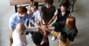group of people putting their hands together in the middle of a huddle